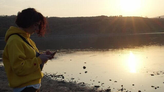 Girl taking photos of a late at sunset