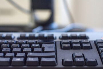 close up view of computer keyboard at table with computer mouse and laptop on blurred background