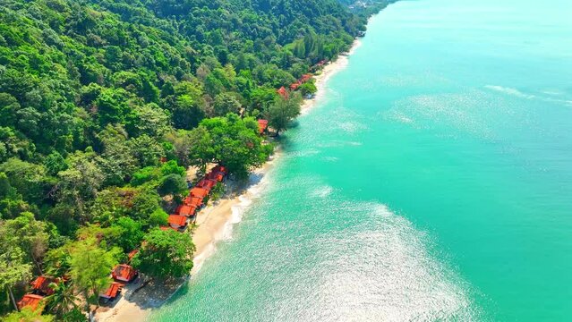 Beaches kissed by turquoise waves, resorts nestled along the shore, emerald forests embracing towering mountains, under a limitless blue sky. Green travel concept. Stock footage. Ko Chang, Thailand.
