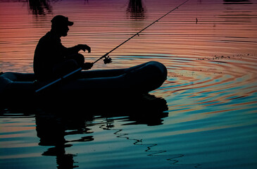 Mature man fishing on the lake from inflatable boa