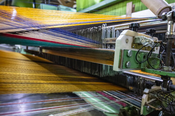 Modern Carpet weaving factory. Carpet making machine needle. Yarn bobbins attached to a carpet...