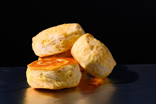 A pile of four can-made biscuits on aluminum foil against a black background