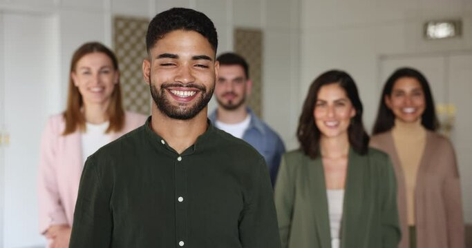 Young Moroccan man, applicant, hired employee, happy ambitious newcomer posing with diverse colleagues or HR managers, recruiters in office. Head shot portrait of professional corporate staff members