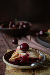 Slice of cherry pie on dark wooden table
