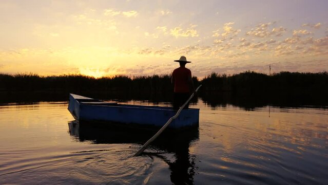 Local fisherman rowing a boat on a river in the early morning hours. person in small wooden boat on calm sea at sunrise