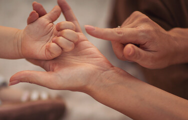 Mother holding hands with her child. Parent play with hands of little kid girl, giving psychological help. Sincere different generations family sharing secrets or making peace.