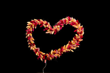 dried flowers tied as heart shape on black background with space for text