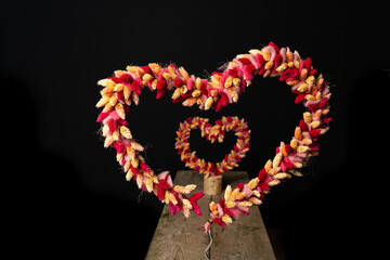 two heart shape of dried flowers with a view through with black background and space for text
