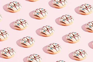 Luxurious decorated glazed donuts with crystals and pearls, creative food pattern on a pastel pink background.