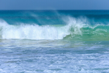 Wave with azure water and white foam approaches on a windy day at Boa Vista's beach, Cape Verde.