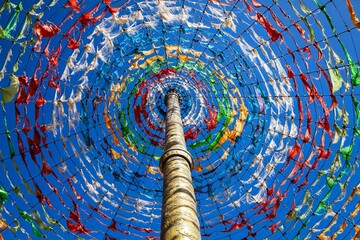 Vibrant Tibetan prayer flags form a captivating circular display around a central pole against a...
