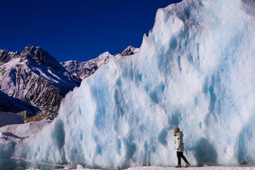 An explorer immersed in the breathtaking splendor of the Laigu (Lhegu) Glaciers, surrounded by towering crystalline seracs, near the serene Rawu Lake nestled in the heart of Tibet's Baxoi County. 