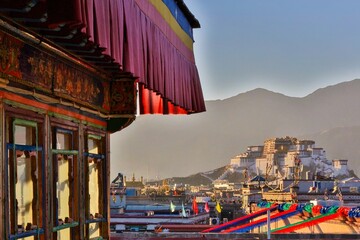 Vibrant Tibetan windows overlook the majestic Potala Palace at sunset in Lhasa, evoking the essence...