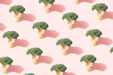 Broccoli, creative vegetable pattern on a pastel pink background.