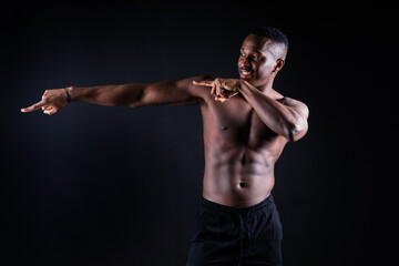 One young african muscular build man standing topless silhouette isolated on black background