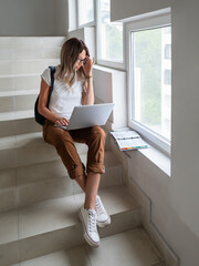 Student is working with laptop on stairs at university campus. Wireless technologies for education. Homework online. Using Internet to search for information. - 721637536