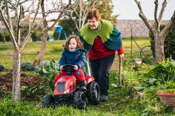 grandmother and grandson playing with a tractor in the garden at home