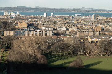 Fototapeta premium Amazing Edinburgh Cityscape with Holyrood Park and Leith docks seen from the top of Salisbury Crags. Destinations in Europe, Space for text, Selective focus.
