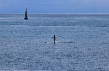 A man on his paddle boat has equal pleasure as the sailboat - scenes from Bayfield, Huron County,...