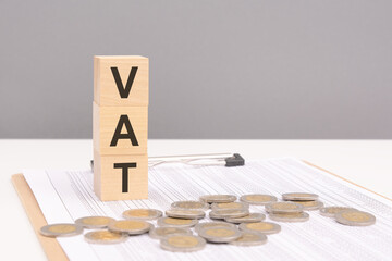 wooden cubes on a brown background with the text VAT - an abbreviation for Value Added Tax. strong...