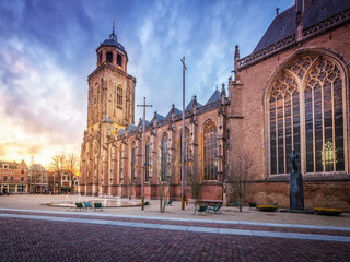 Fototapeta premium a clock tower in front of a church at sunset - fotograno af