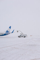 De-icing the aircraft before the flight. The deicing machine sprinkles the wing of a passenger...