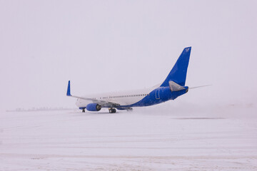 White passenger airplane landing runway on snowy airport