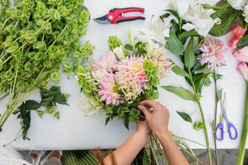 Florist Crafting a Pink Dahlia Bouquet. Florist at work. Workplace. Small business. Background.