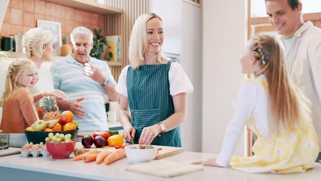 Big family, dinner and happy cooking in kitchen with vegetables, food and nutrition in home. Heathy, diet or mother meal prep salad with hungry child eating fruit or strawberry on table with wellness