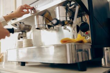 Close up of female barista making coffee in a coffee machine working in cafe. High quality photo