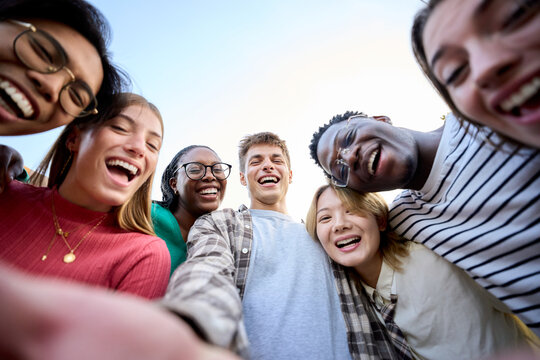 Selfie Portrait large group multiracial friends posing smiling and looking to camera. Happy young people hugging together standing outdoors. Photo of gen z guys and girls enjoying spring vacation day