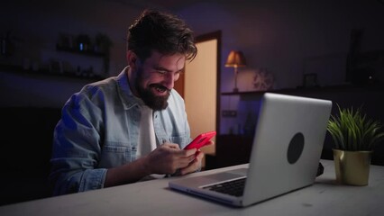 Happy young man competitor checking pass lists on laptop. Excited professional winner celebrates success receiving new job opportunity civil servant sends voice message from mobile phone at night home