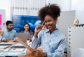 Portrait of happy young african businesswoman with group of office worker on meeting with screen...