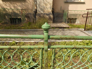 A fragment of a green metal fence and the wall of the building behind