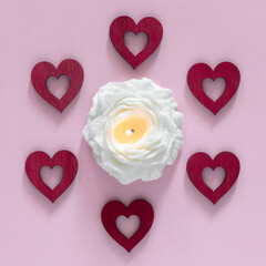 Pink background with red hearts and candle in flower shape. Valentine day and love concept.