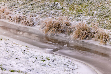 Frozen stream with ice and snow at the edge of the water