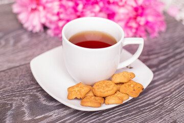 Sweet morning breakfast - cup of tea, cookies and bouquet of peonies flowers