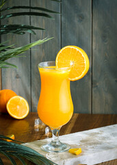 fresh orange juice ,orange in the background and tree part wooden brown floor and green wooden background
