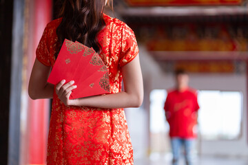 Couple giving red envelopes for Lunar New Year celebrations. Hand hold red packet. Chinese new year...
