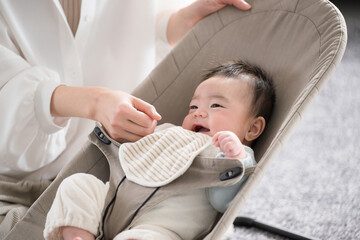 ニコニコあやされるバウンサーにのるかわいい笑顔の赤ちゃん