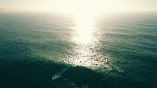 Aerial view. The green ocean in soft sunset rays, big waves, surfers and jet skis.  4k stock video