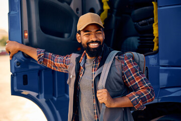 Happy African American truck driver getting in vehicle cabin.