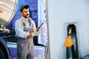 Mid adult worker refueling the gas tank of a truck.