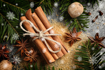 Different spices and fir tree branches on grey background, flat lay. Cinnamon, anise, nutmegs,...