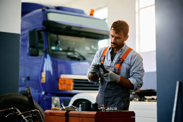Mid adult truck mechanic working in garage.
