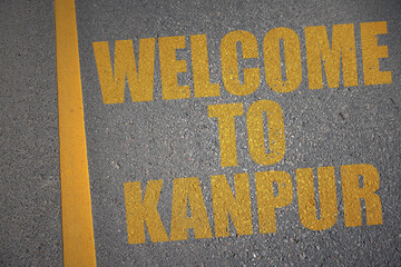 asphalt road with text welcome to Kanpur near yellow line.