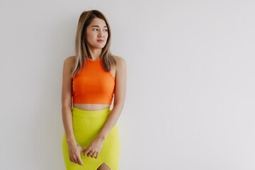 Serious upset face of asian woman in orange lemon color isolated on white.