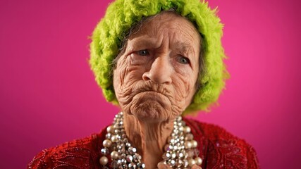 Slow motion funny view of mature elderly woman, 80s, having giving OKAY gesture, wearing green wig...