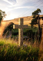 A cross marking a headstone in a quiet graveyard