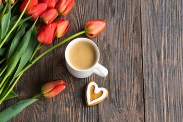Fototapeta na wymiar Fresh orange tulips and cappuccino mug with spring composition. Greeting card with copy space for Valentine's Day, Woman's Day and Mother's Day.
